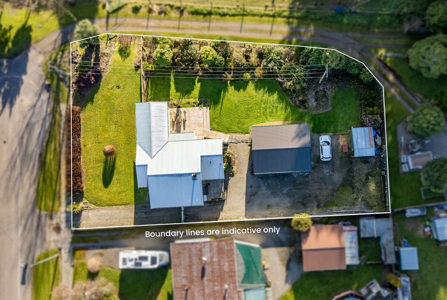 Aerial drone view of a residential property with boundary lines marked, featuring a house, garage, and large green yard.