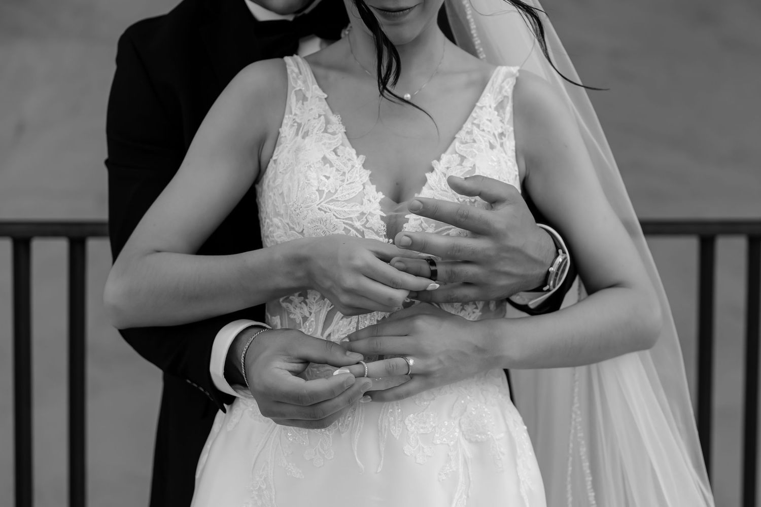 Black and white detail shot of hands clasped together during wedding ceremony.