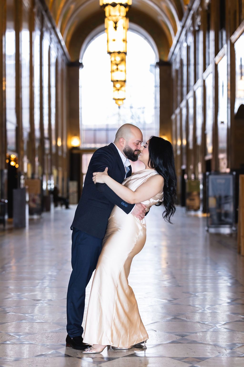 A romantic moment captured in an elegant corridor with arched ceilings and warm lighting.