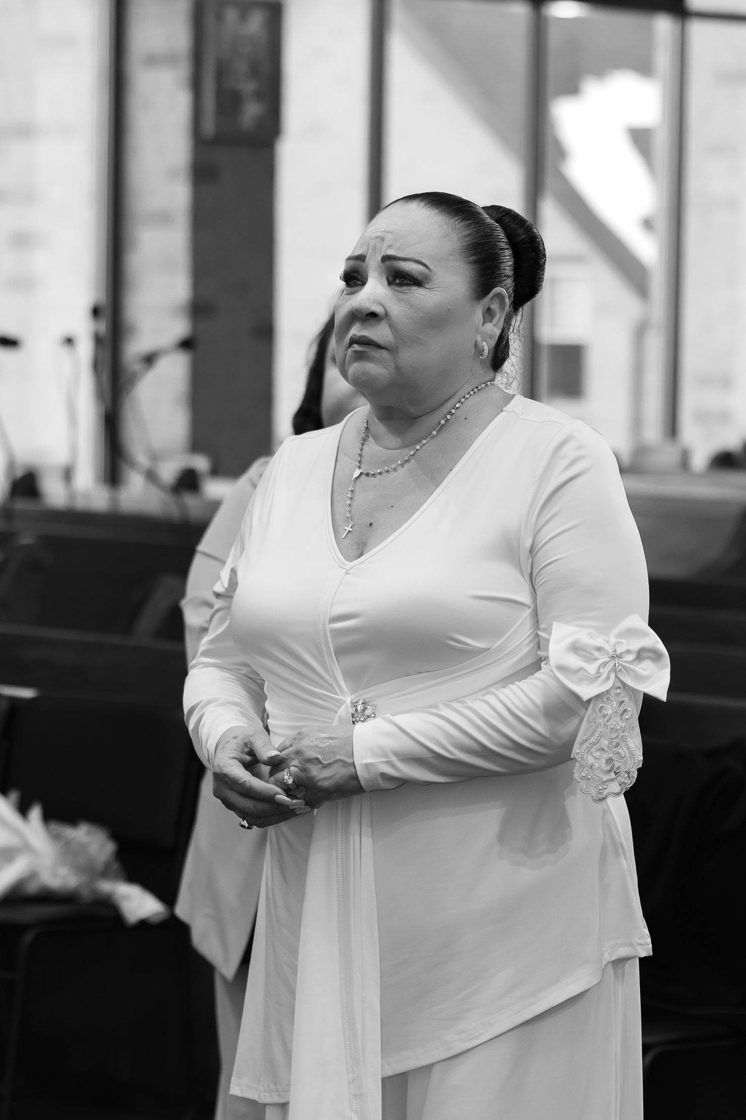 Black and white portrait of woman in formal white dress with lace details during ceremony.