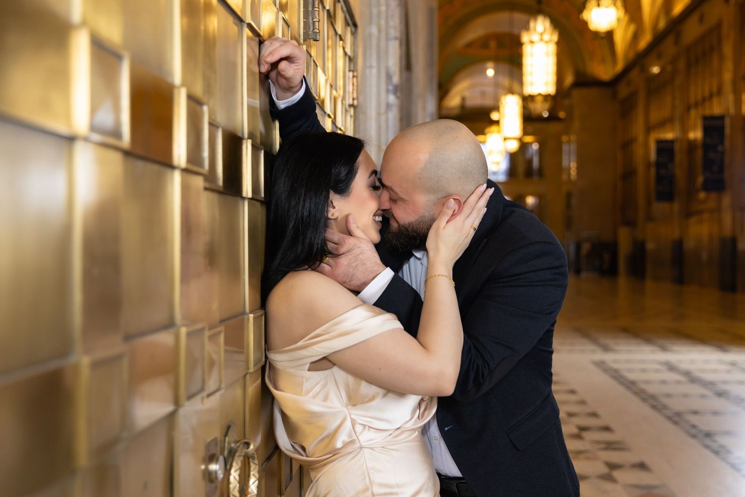 Couple shares a passionate moment in an elegant hallway with champagne-colored walls.