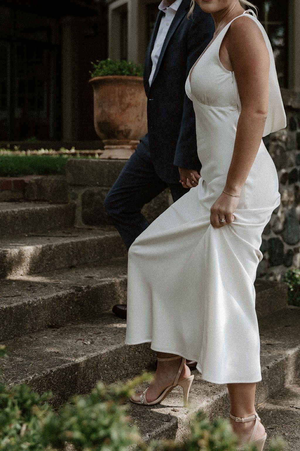 A couple descends stone steps together, with the bride's white dress flowing elegantly.