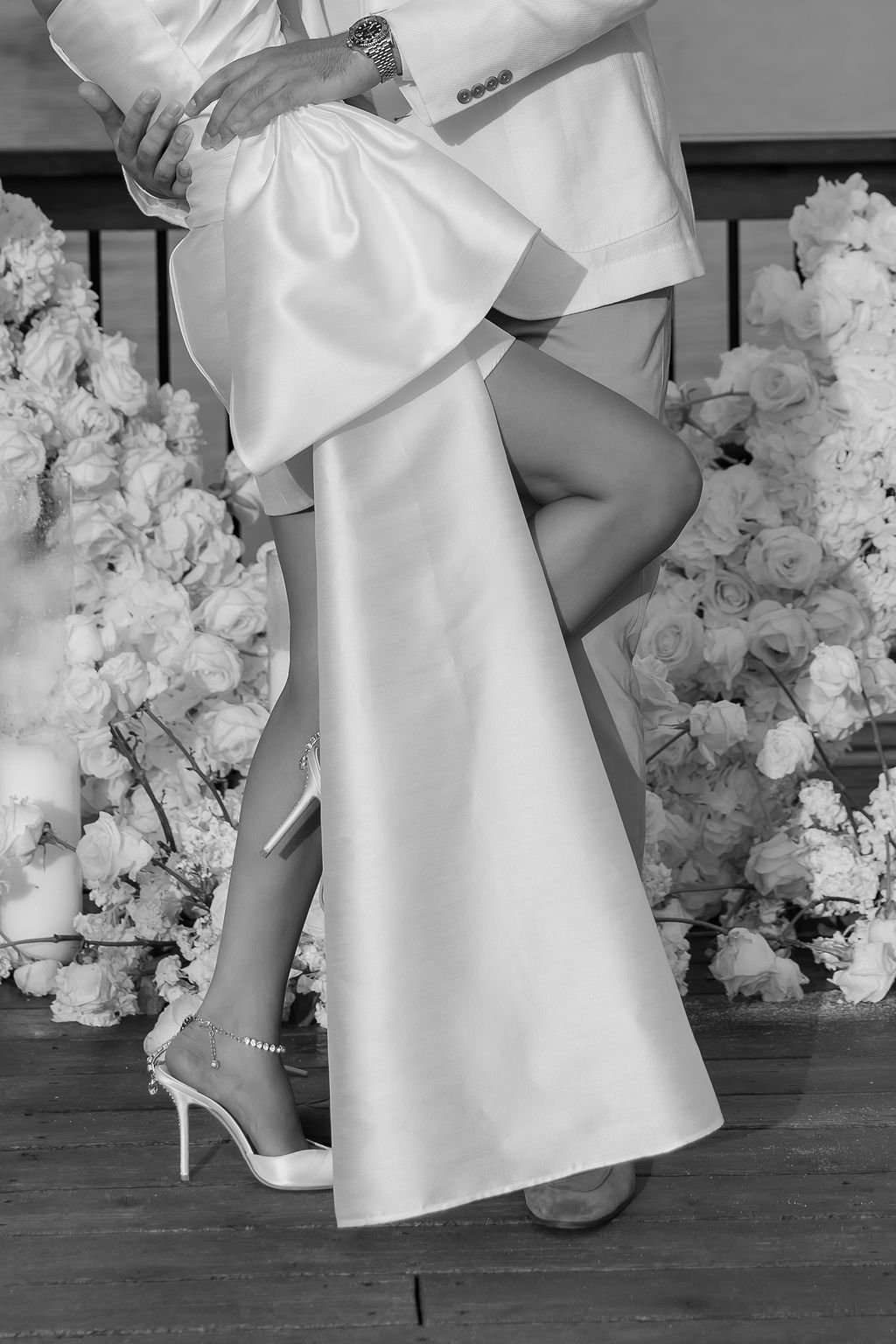 Black and white photo of elegant wedding dress with flowing fabric and high heels.
