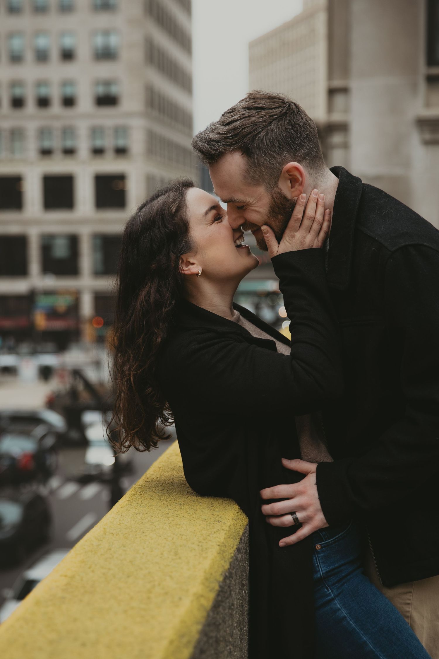 A romantic embrace captured on an urban rooftop with city buildings in the background.