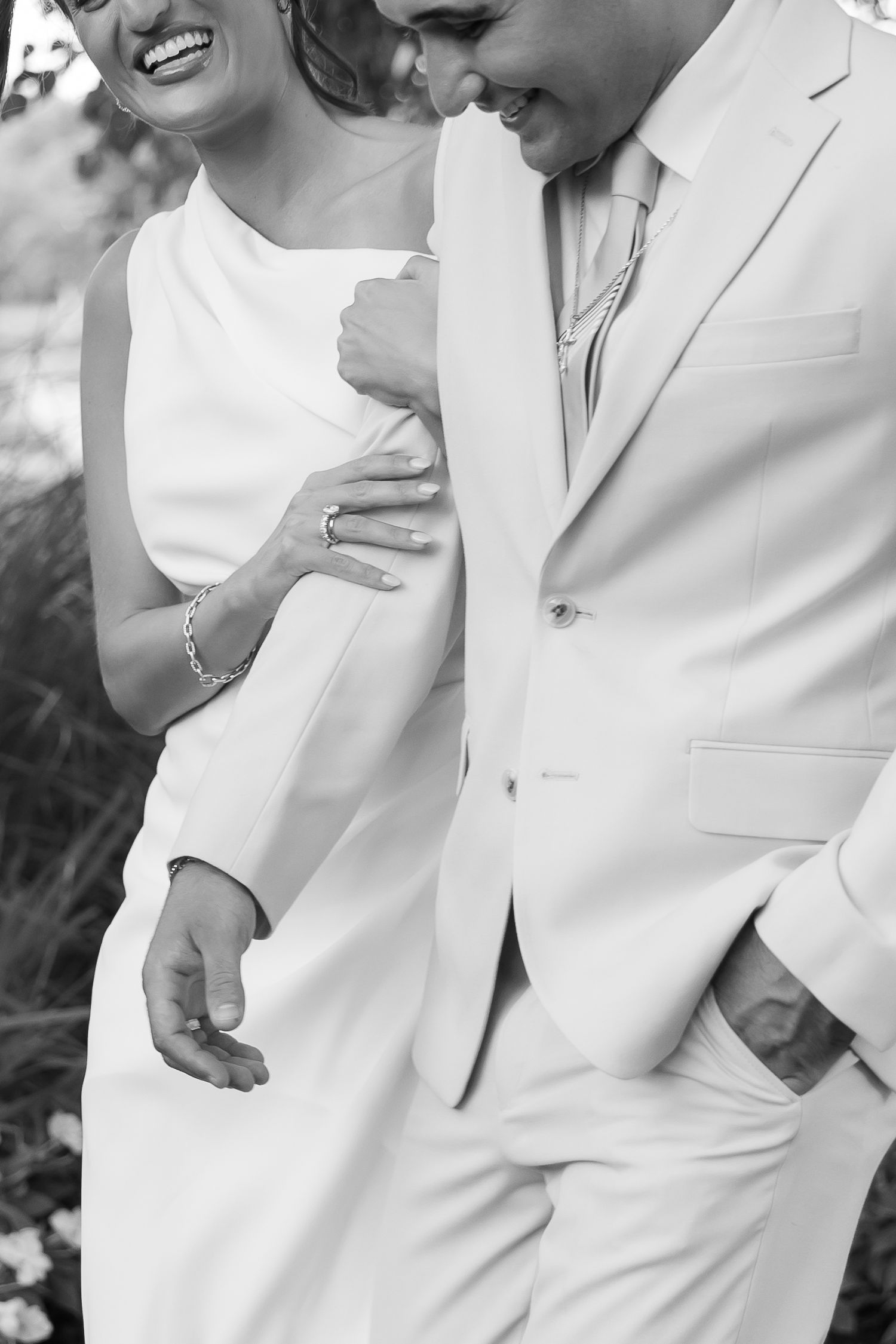 A joyful couple in white attire sharing a candid laughing moment together.