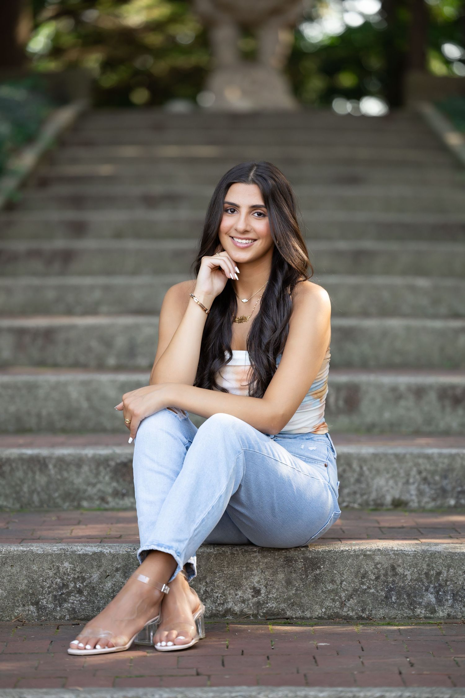 Casual portrait of woman sitting on stone steps outdoors wearing light denim.