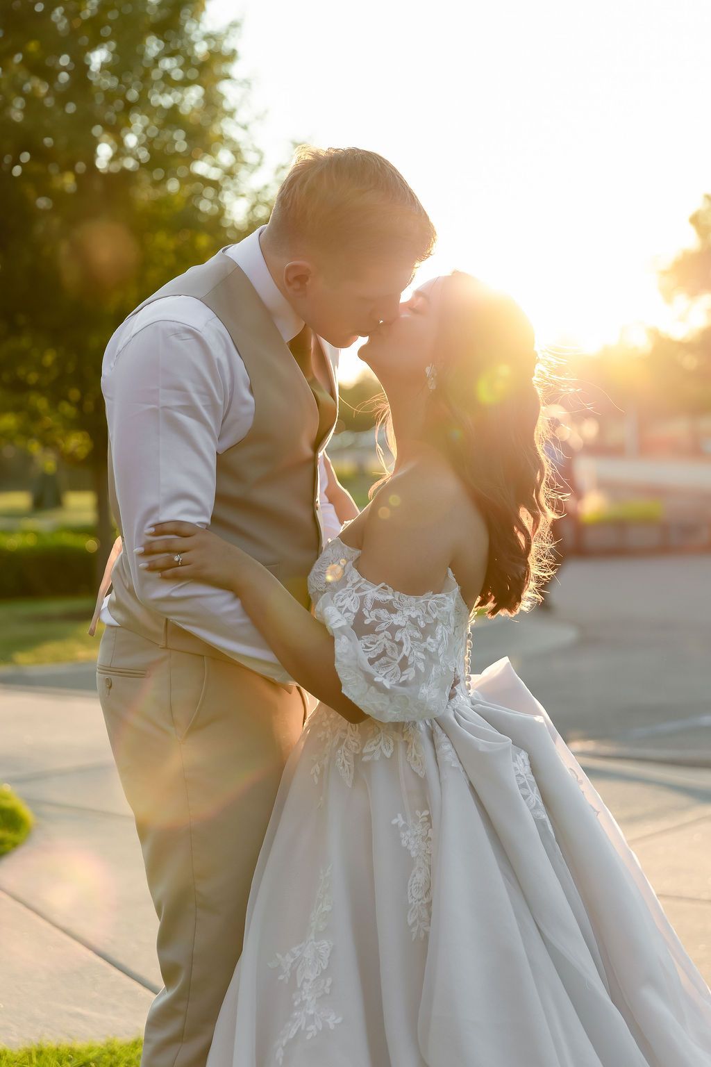 A bride and groom share an intimate moment at sunset, with golden light illuminating their embrace.