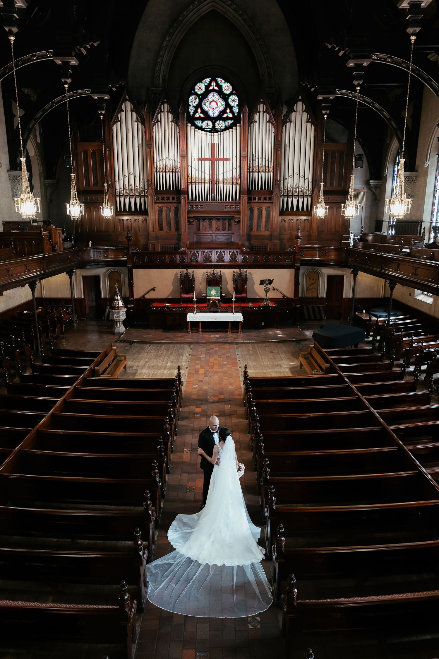 Dramatic wide shot of a church wedding ceremony with pipe organ and wooden pews.