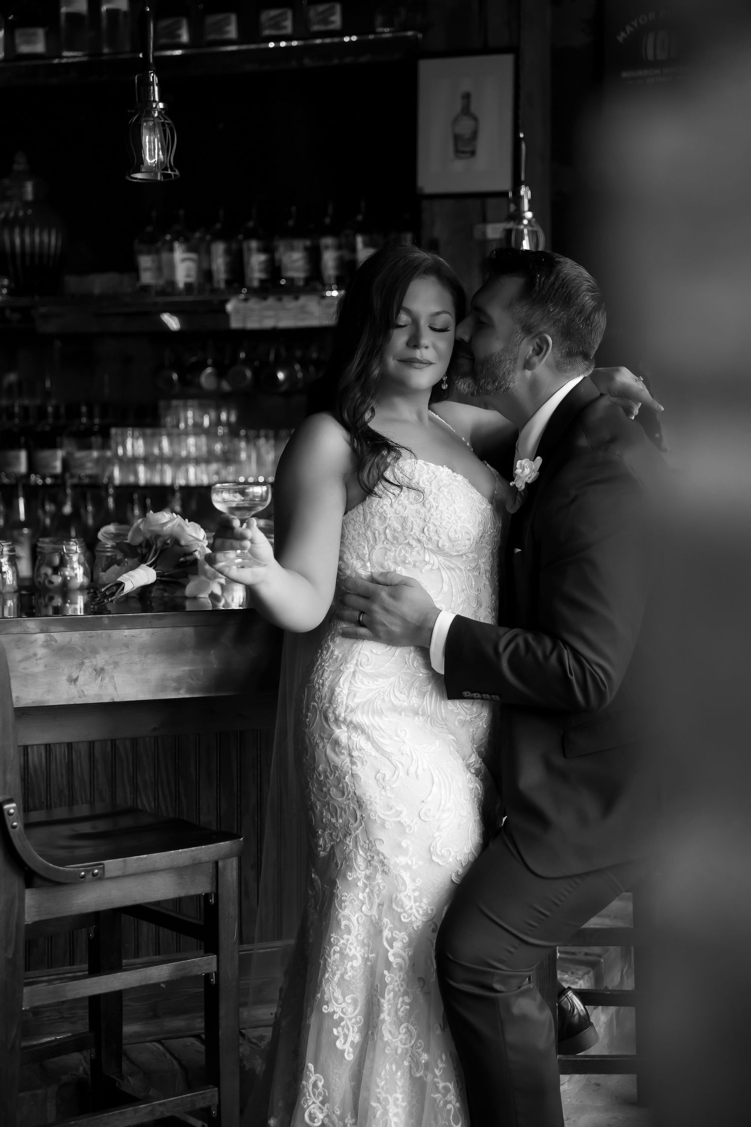 A romantic moment captured in black and white at an elegant bar setting.