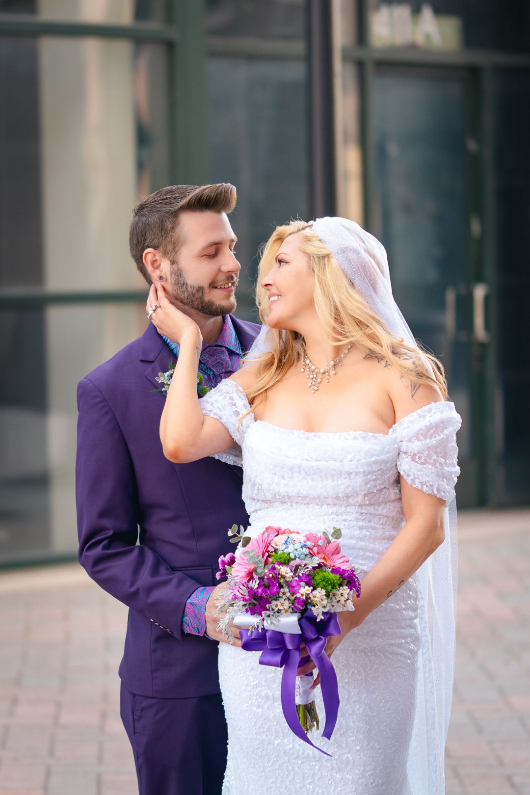 Romantic wedding portrait with couple in purple suit and white lace dress.