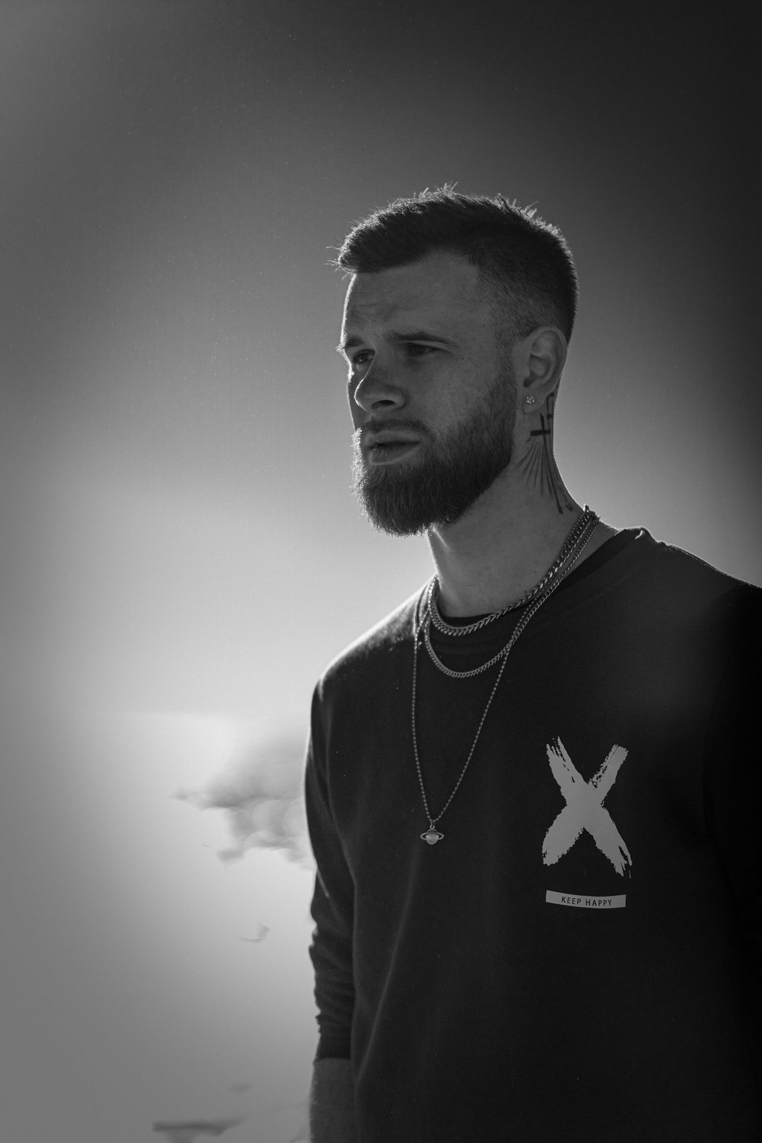 Black and white portrait with dramatic side lighting against gradient background.