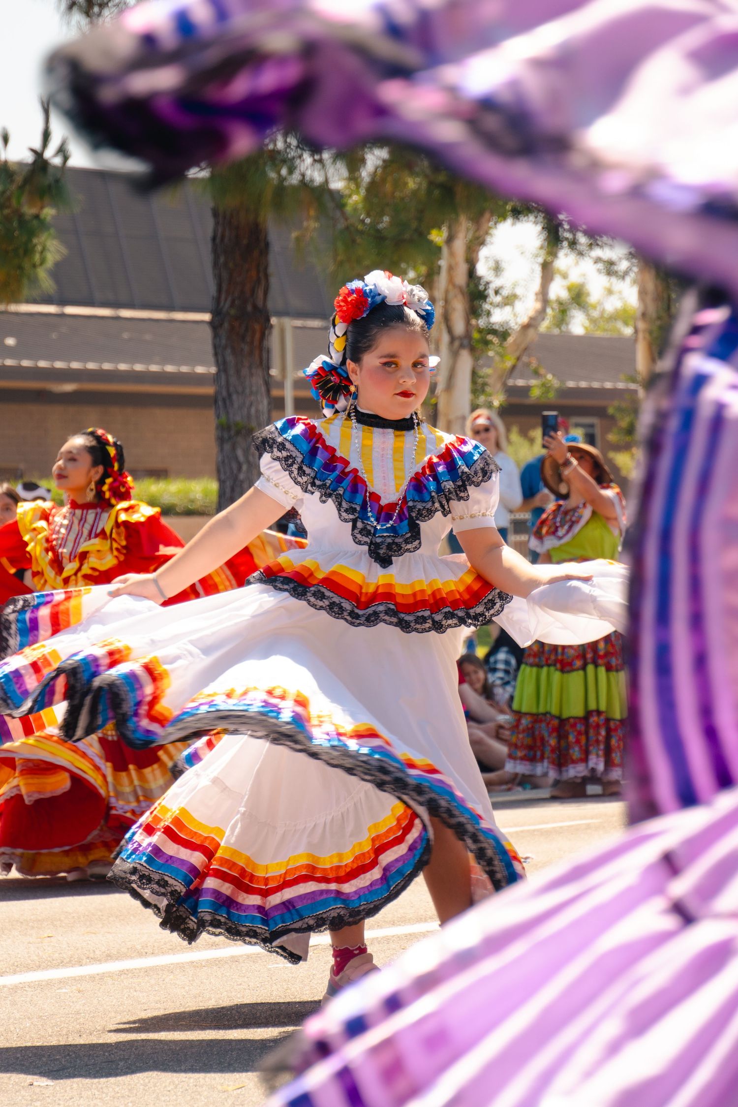 Dancer in colorful traditional Mexican folkloric dress spins during cultural performance with vibrant ruffled skirt.