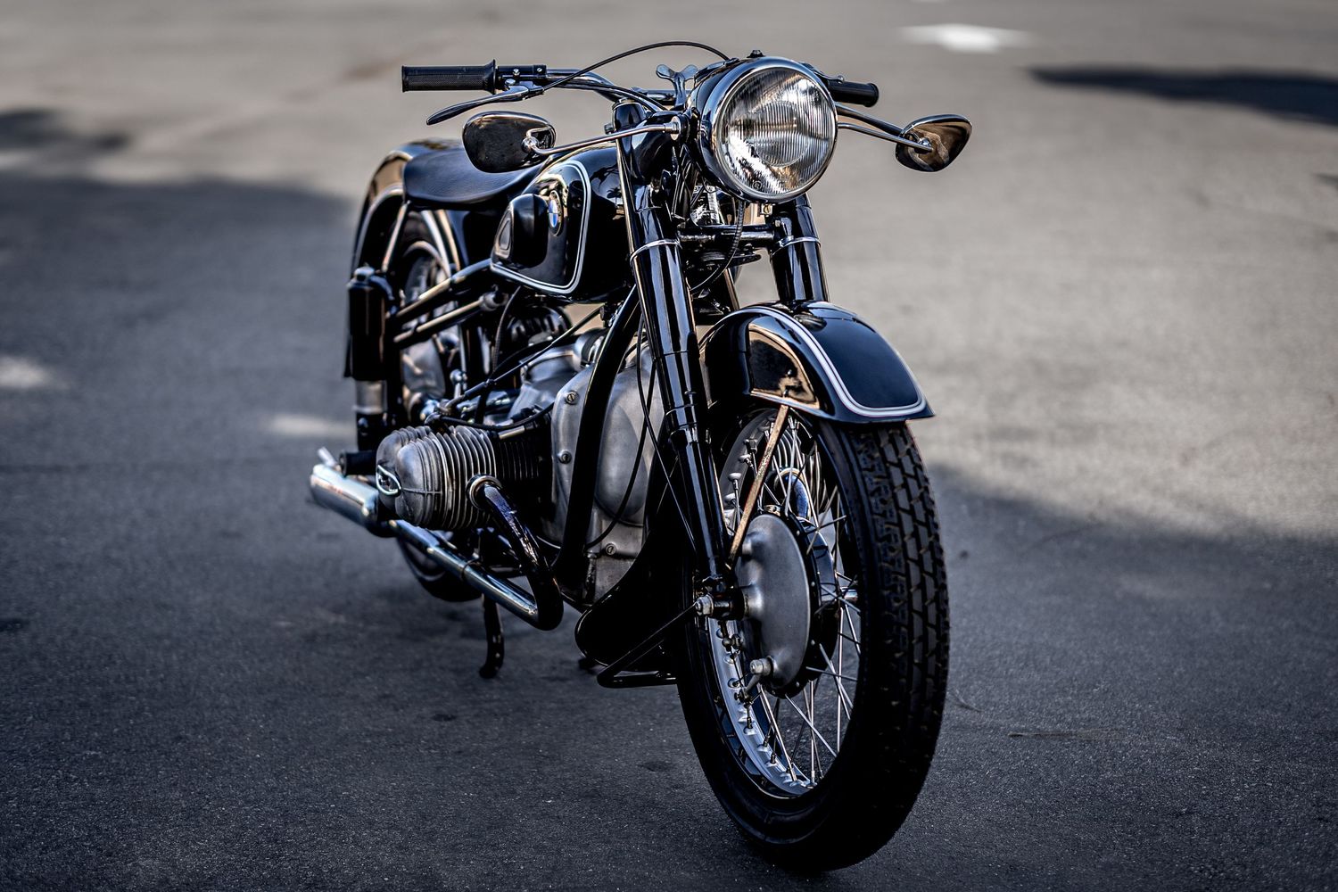Custom vintage black BMW motorcycle with chrome accents parked on asphalt in dramatic lighting.