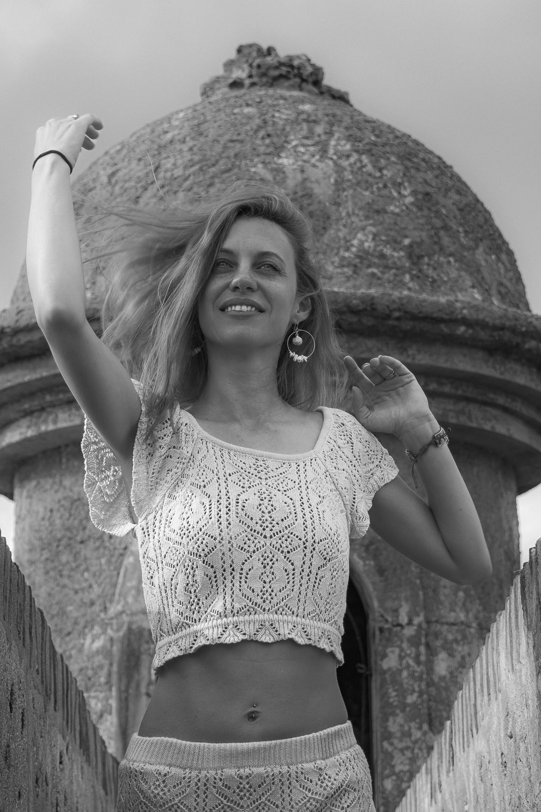 White lace outfit against historical stone dome architecture in black and white.