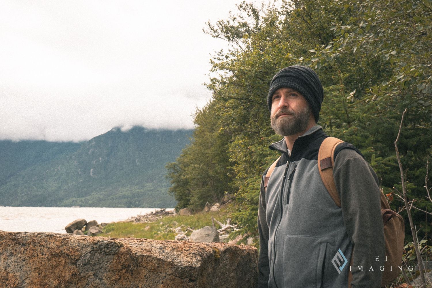 Person in winter gear with backpack hiking near misty mountain lake.
