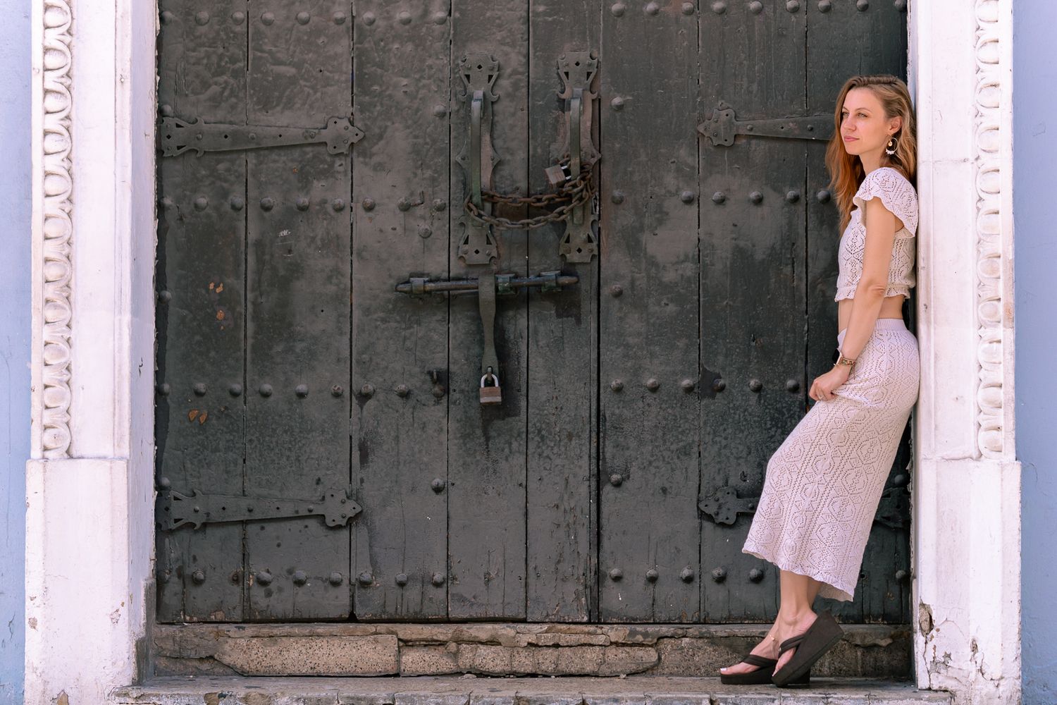 Artistic pose against rustic dark wooden door in vintage style dress.