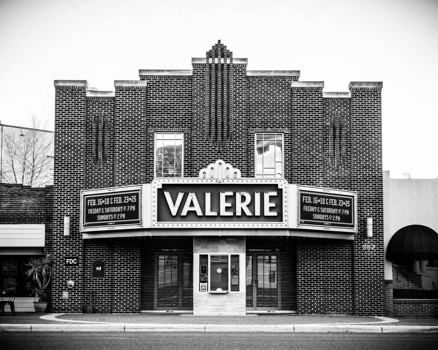 A black and white photo of the historic Valerie Theatre with art deco brick architecture and vintage marquee signage.