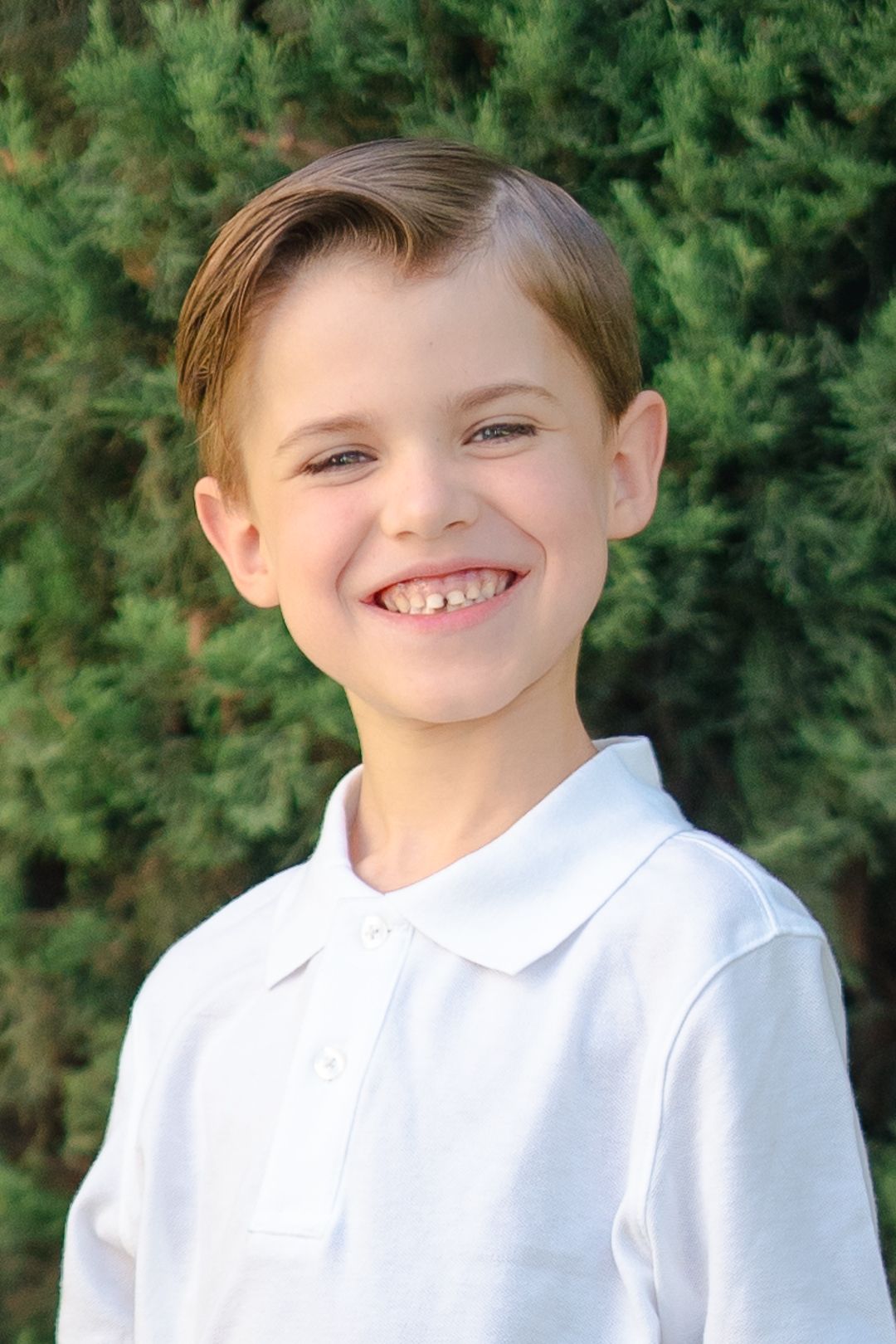Close-up school portrait of student in white polo against green background.