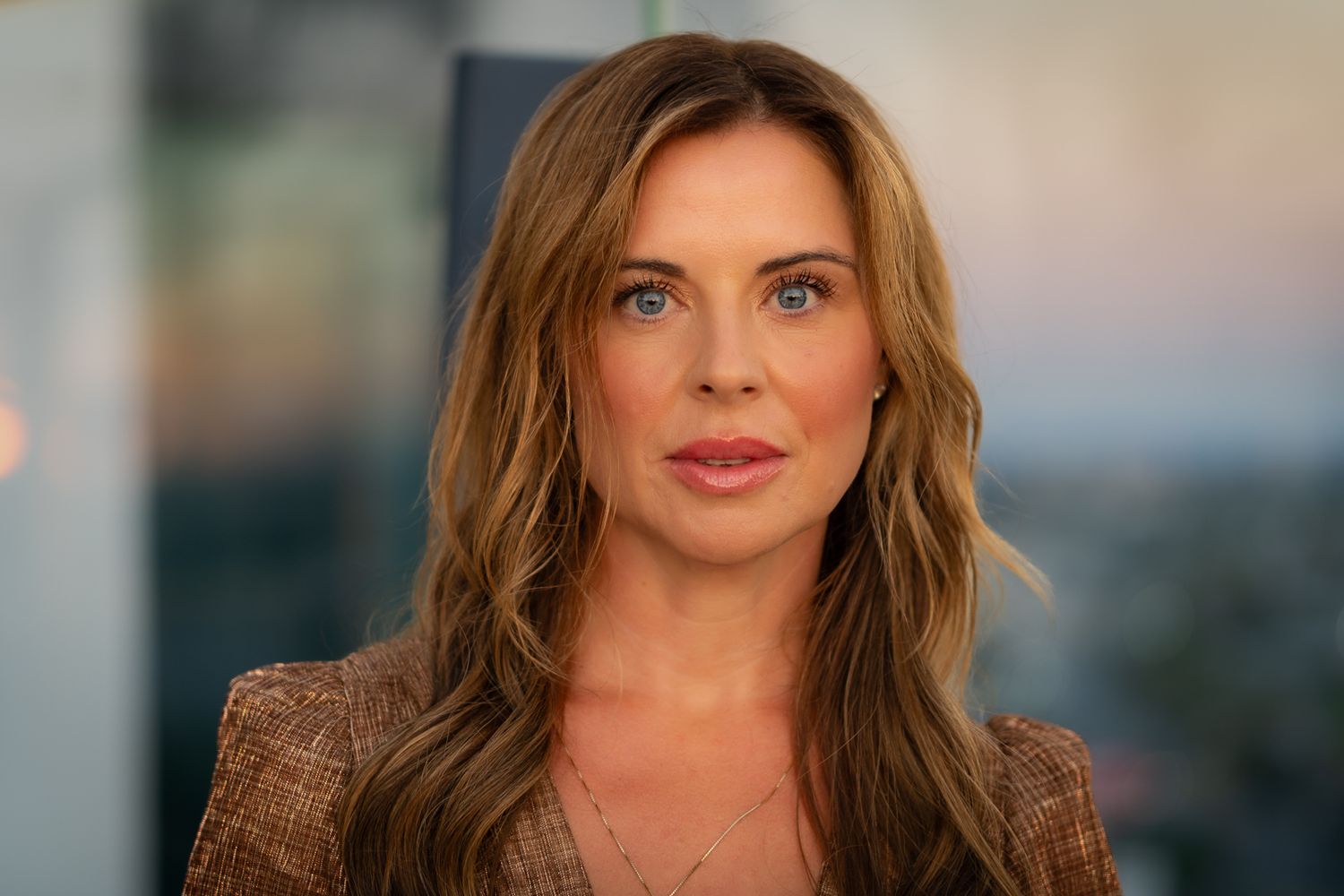 Professional portrait featuring warm lighting and natural makeup against an urban background.