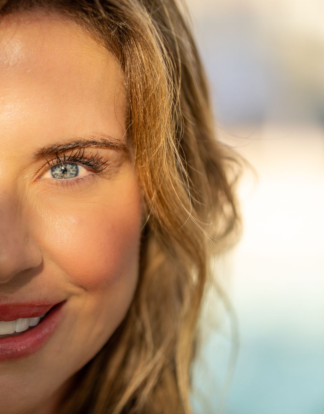 Close-up beauty shot focusing on bright blue eyes, natural makeup and glowing skin.