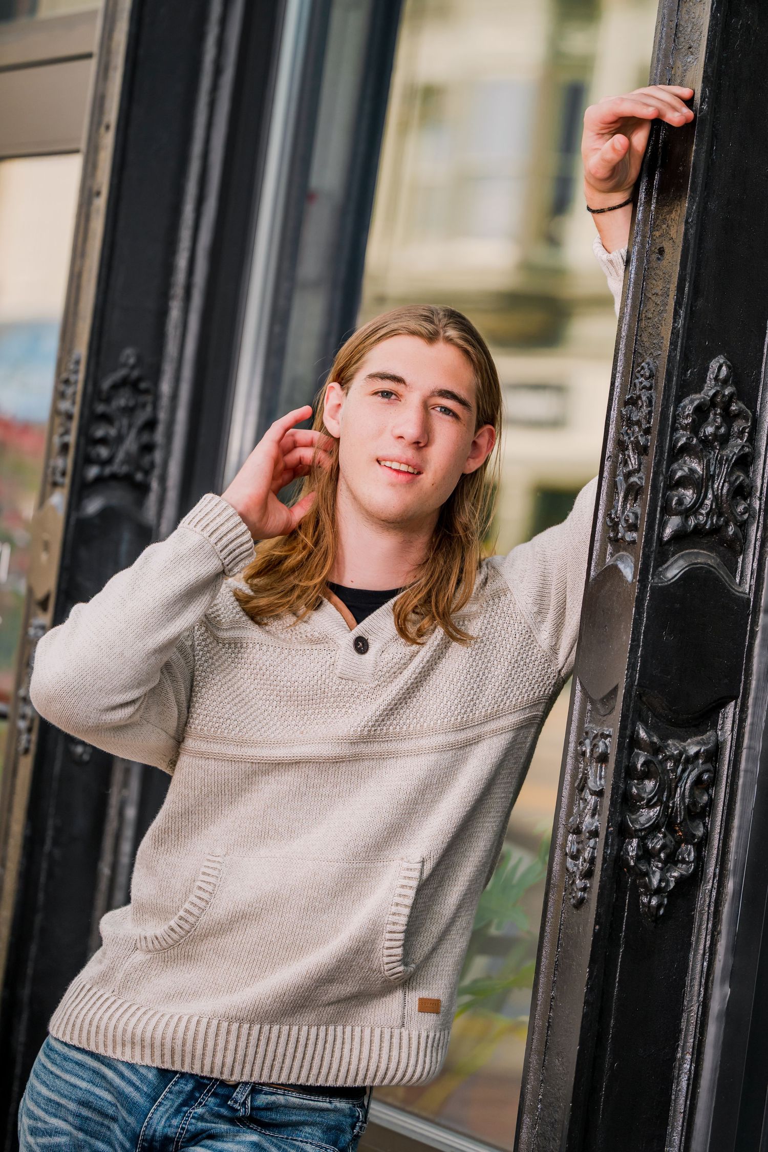 Three lifestyle portraits of someone in a beige sweater leaning against decorative metal railings outdoors.