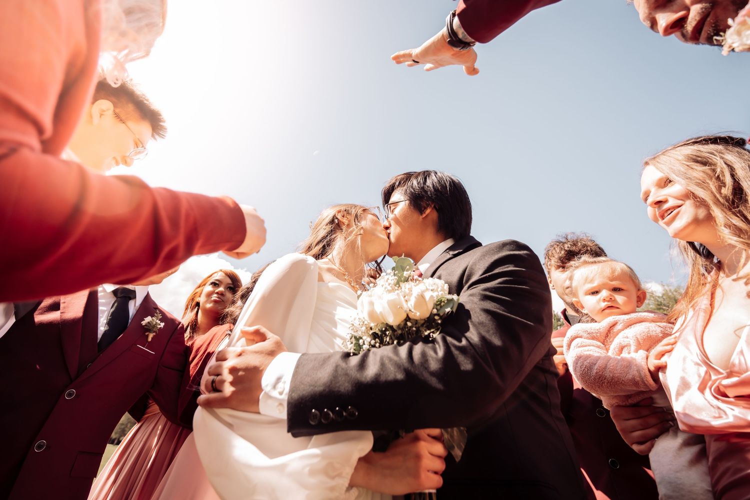 A joyful outdoor celebration moment where people raise their hands and capture photos during a festive gathering.