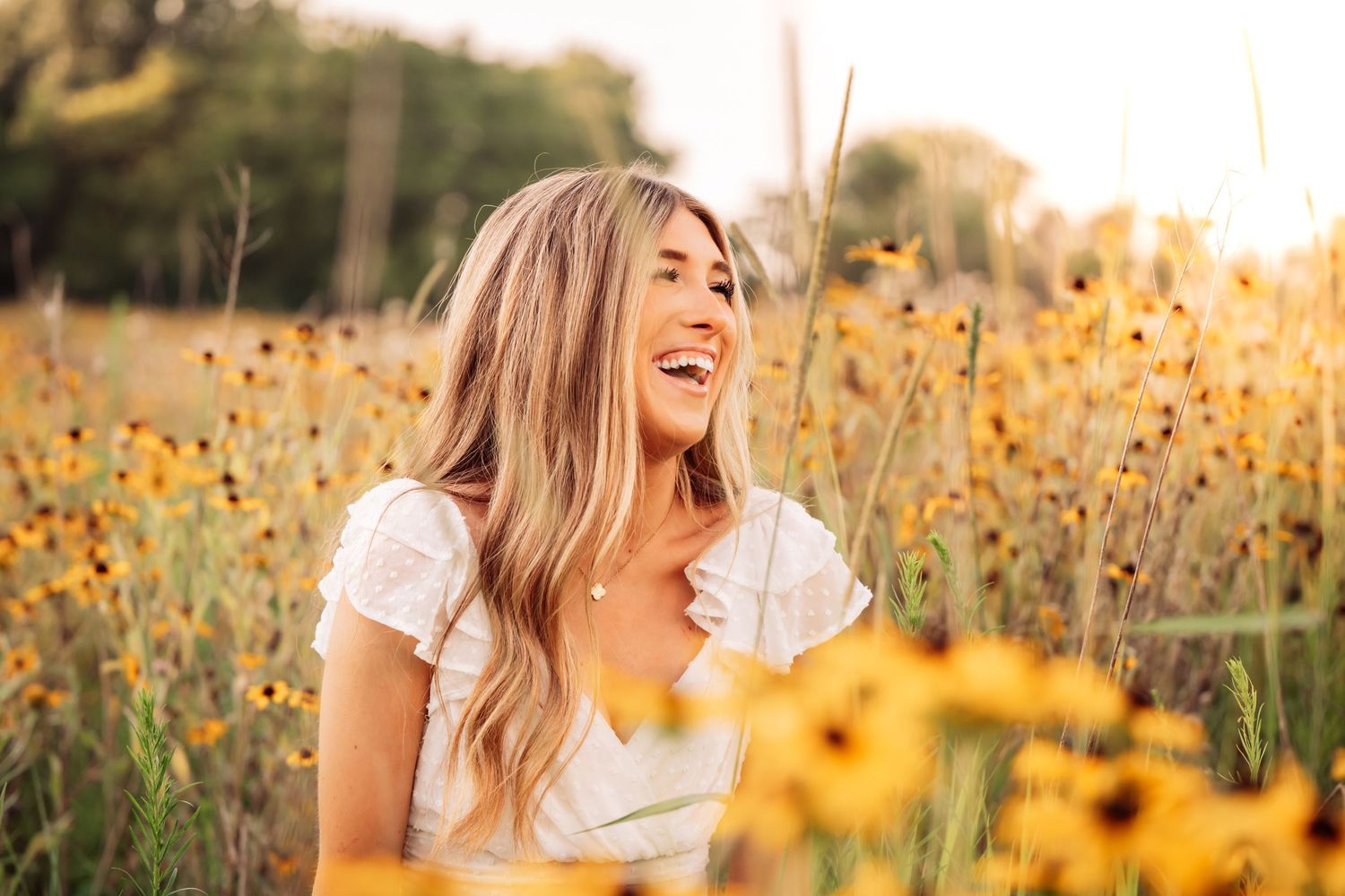 A person sits in a golden sunflower field at sunset creating a warm and dreamy portrait setting.
