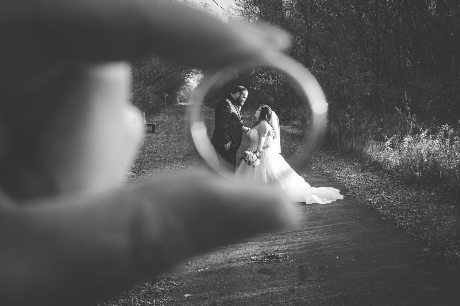 grayscale wedding photo of wedding couple bride and groom through the view of the ring