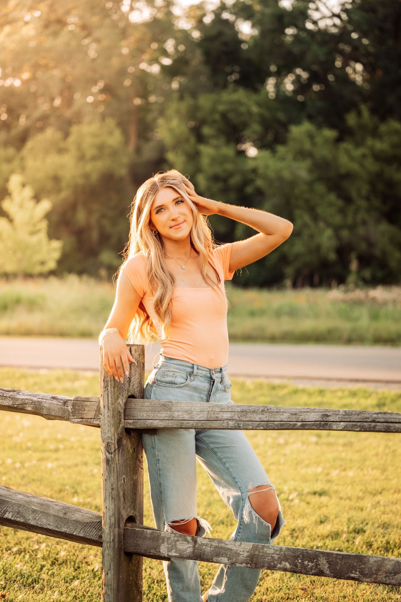 golden hour senior photo of girl next to wooden fence
