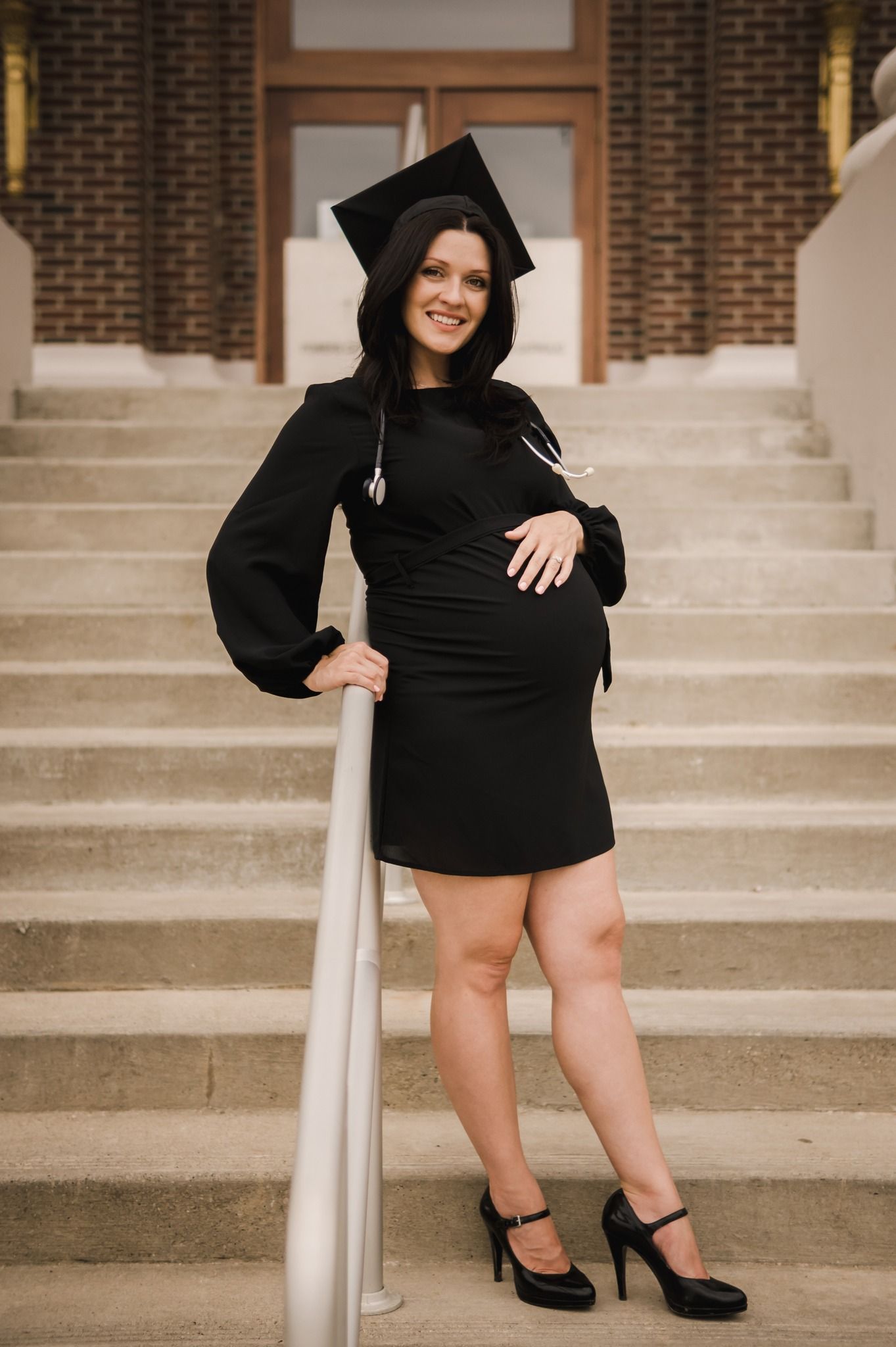 nursing graduate senior photo standing on stairs while pregnant