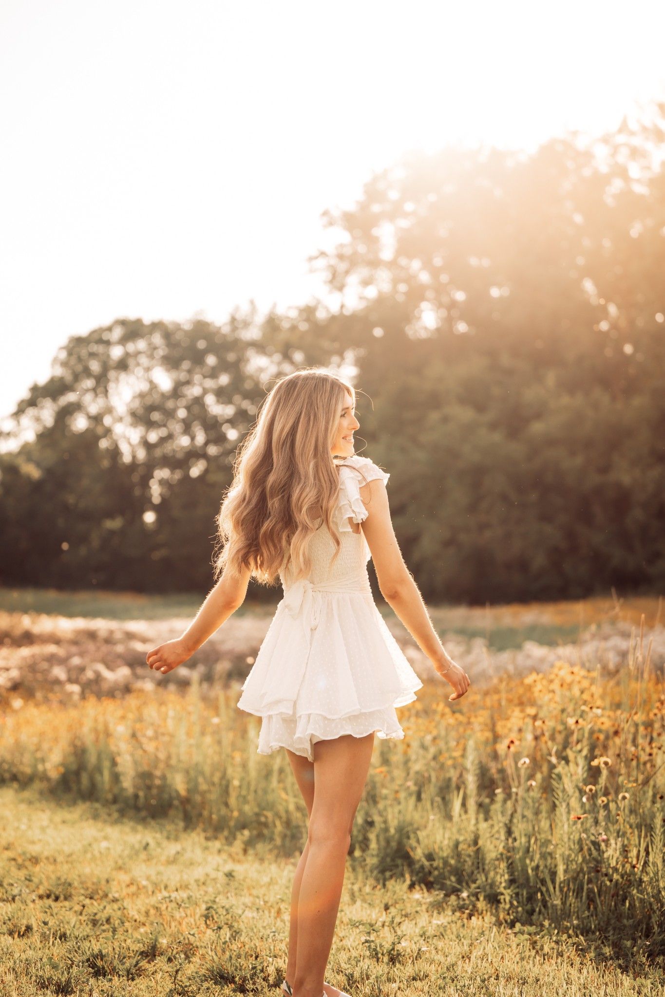 golden hour senior photo of girl in white dress in a field in the fall autumn
