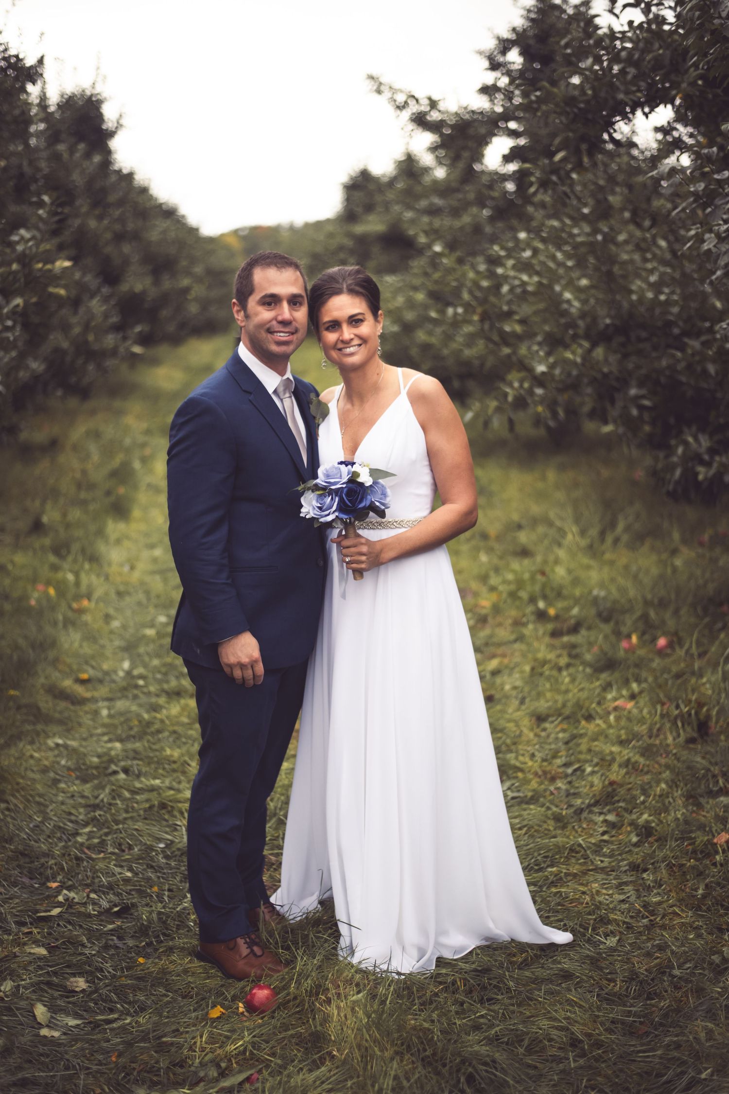 bride and groom in orchard blue green