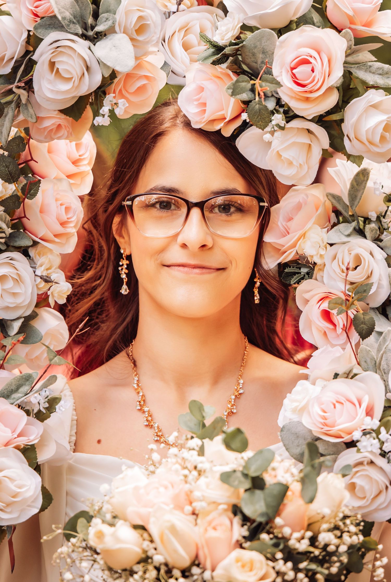 A portrait surrounded by delicate peach and cream colored roses with green foliage creating a romantic floral frame.