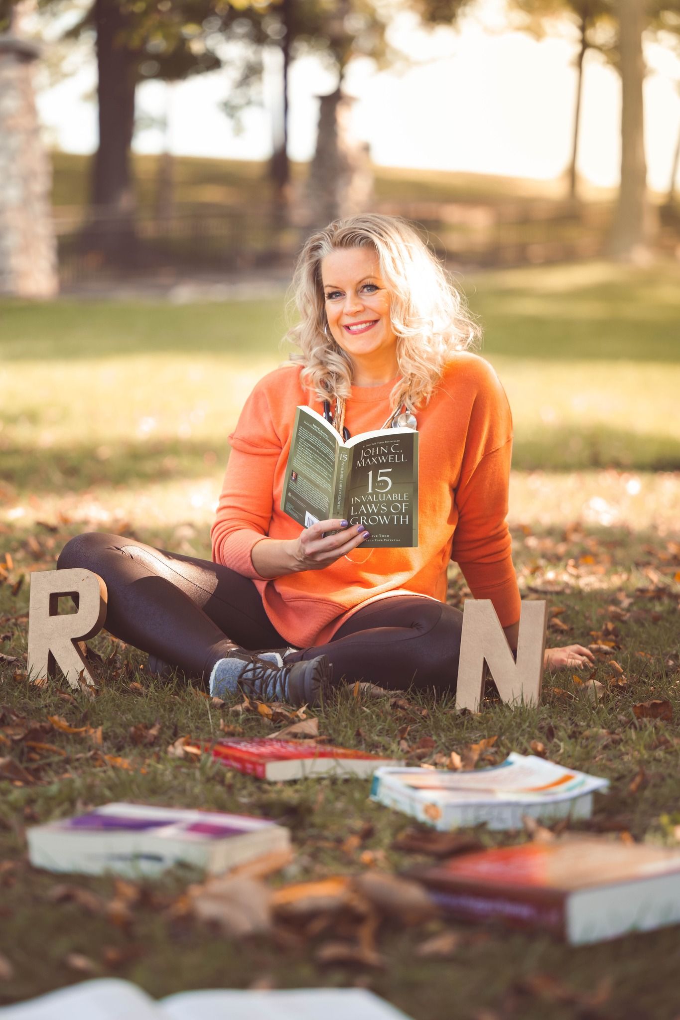 nursing graduate student sitting on grass with letter R N while reading a book college senior photos