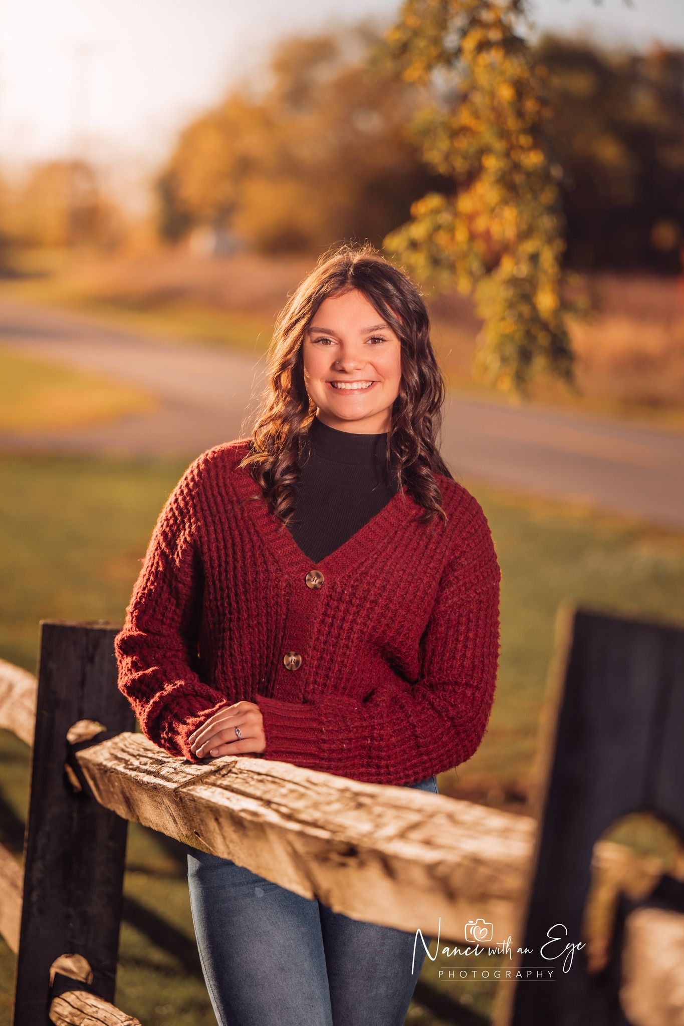 senior photo in fall of girl leaning against a wooden fence golden hour