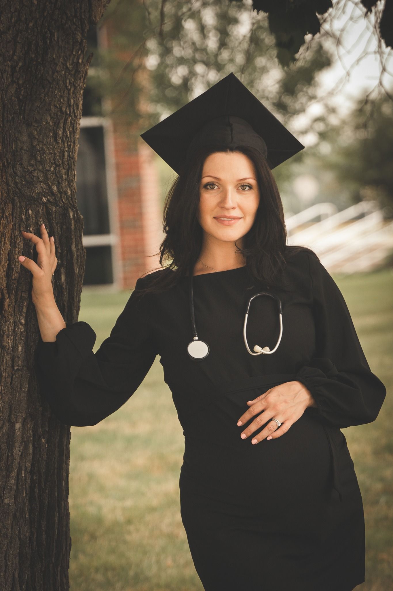 nursing graduate senior photo standing by a tree while pregnant