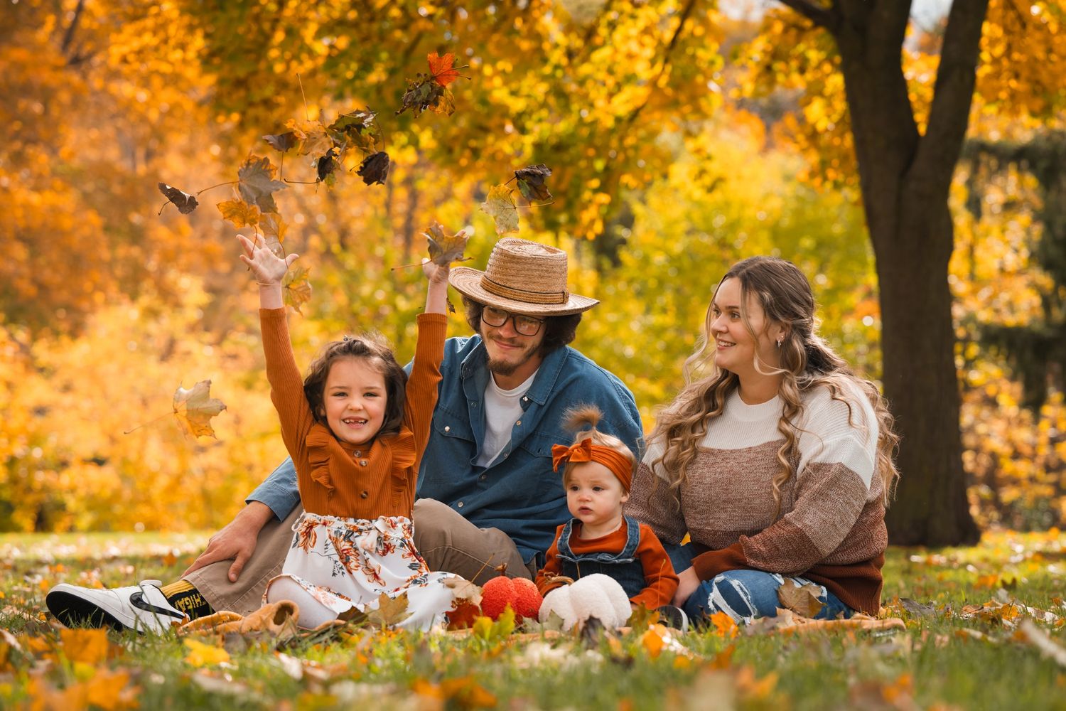 family of four photoshoot in the fall throwing leaves in the air