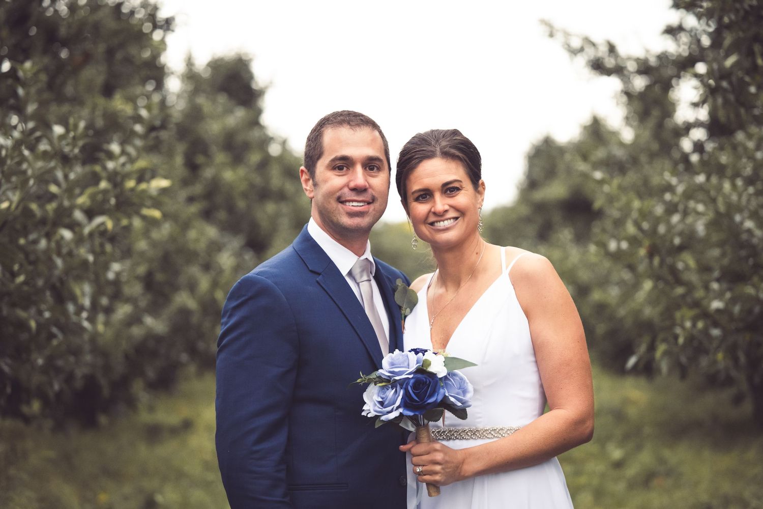 bride and groom in orchard blue green color scheme