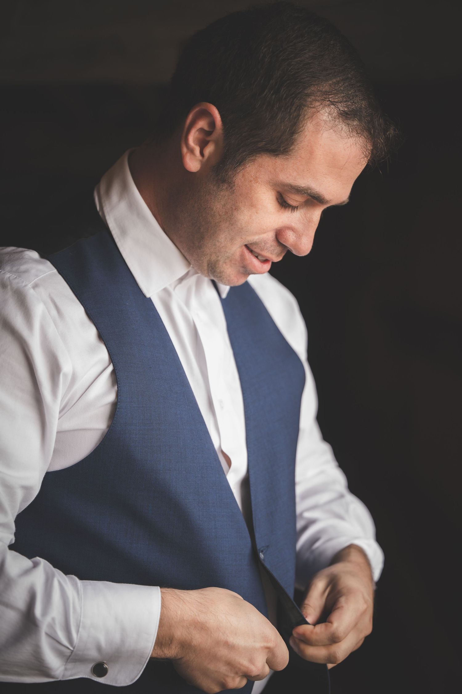 Close-up sequence of someone putting on a blue vest over a white dress shirt, shown from different angles.