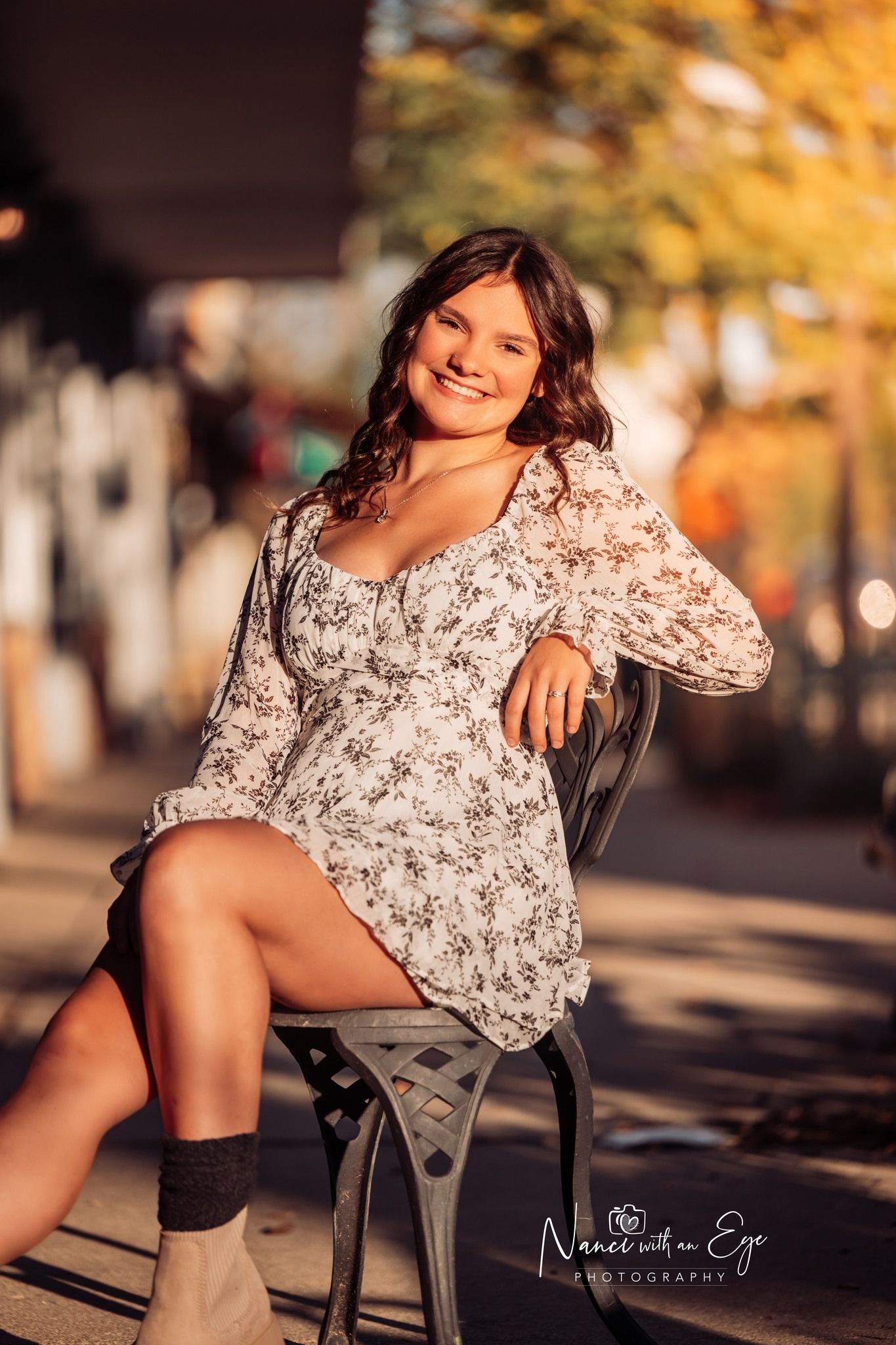 senior photo in fall of girl leaning sitting in chair in downtown setting at golden hour