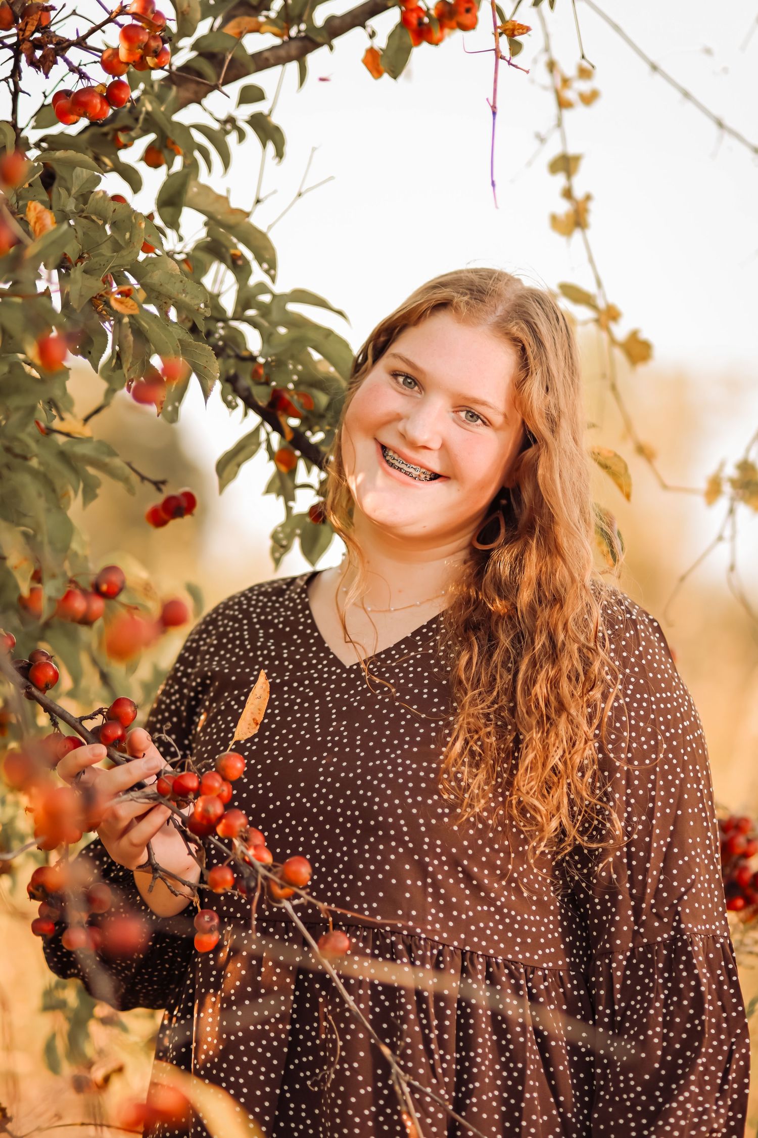 senior photo in fall of redhead girl next to a tree