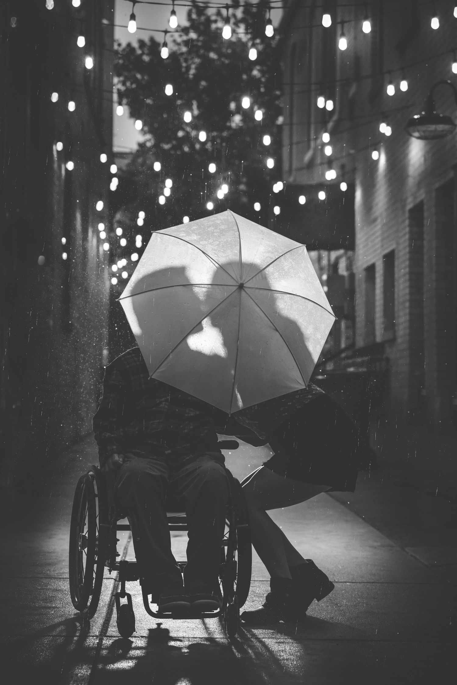engagement photoshoot an night in the rain in an ally with lights wheelchair