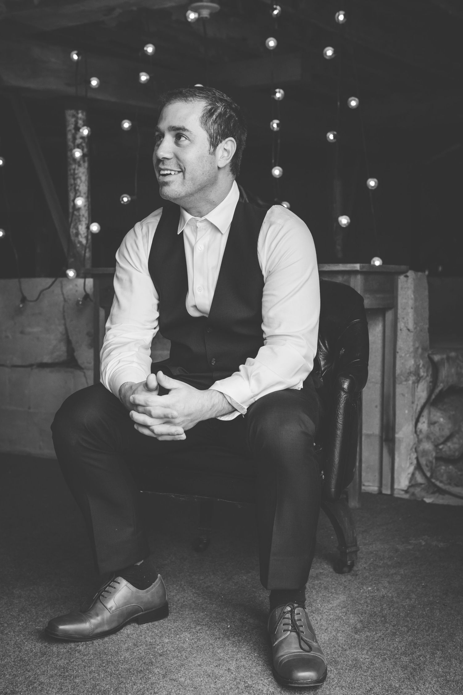 grayscale photo of groom sitting in chair