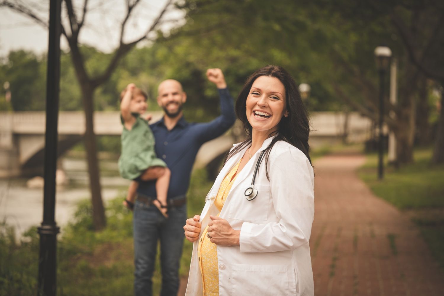 nursing graduate senior photo standing in front of supporting family while pregnant