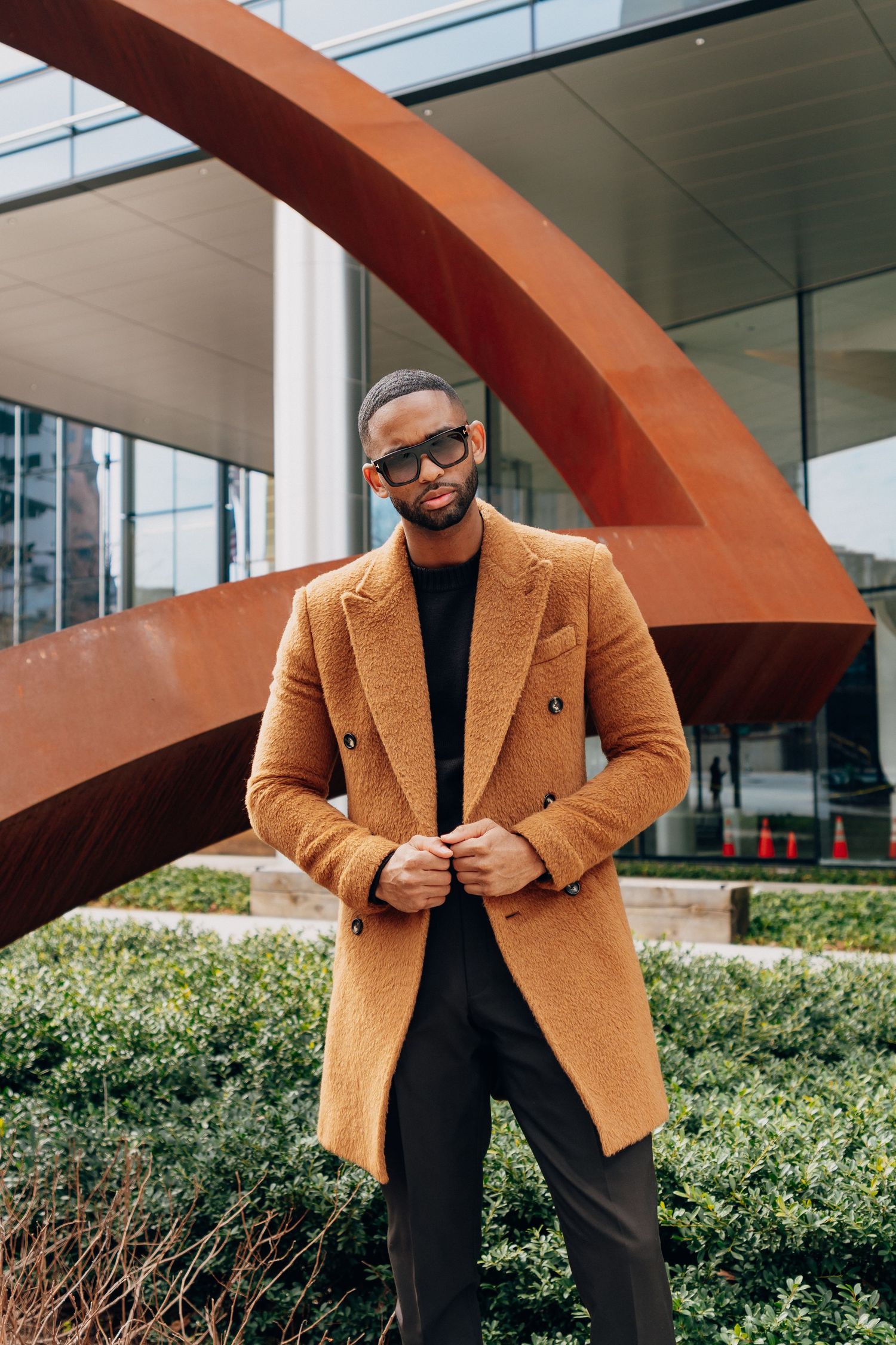 Stylish outdoor fashion shots featuring tan blazer and black turtleneck against modern architecture.
