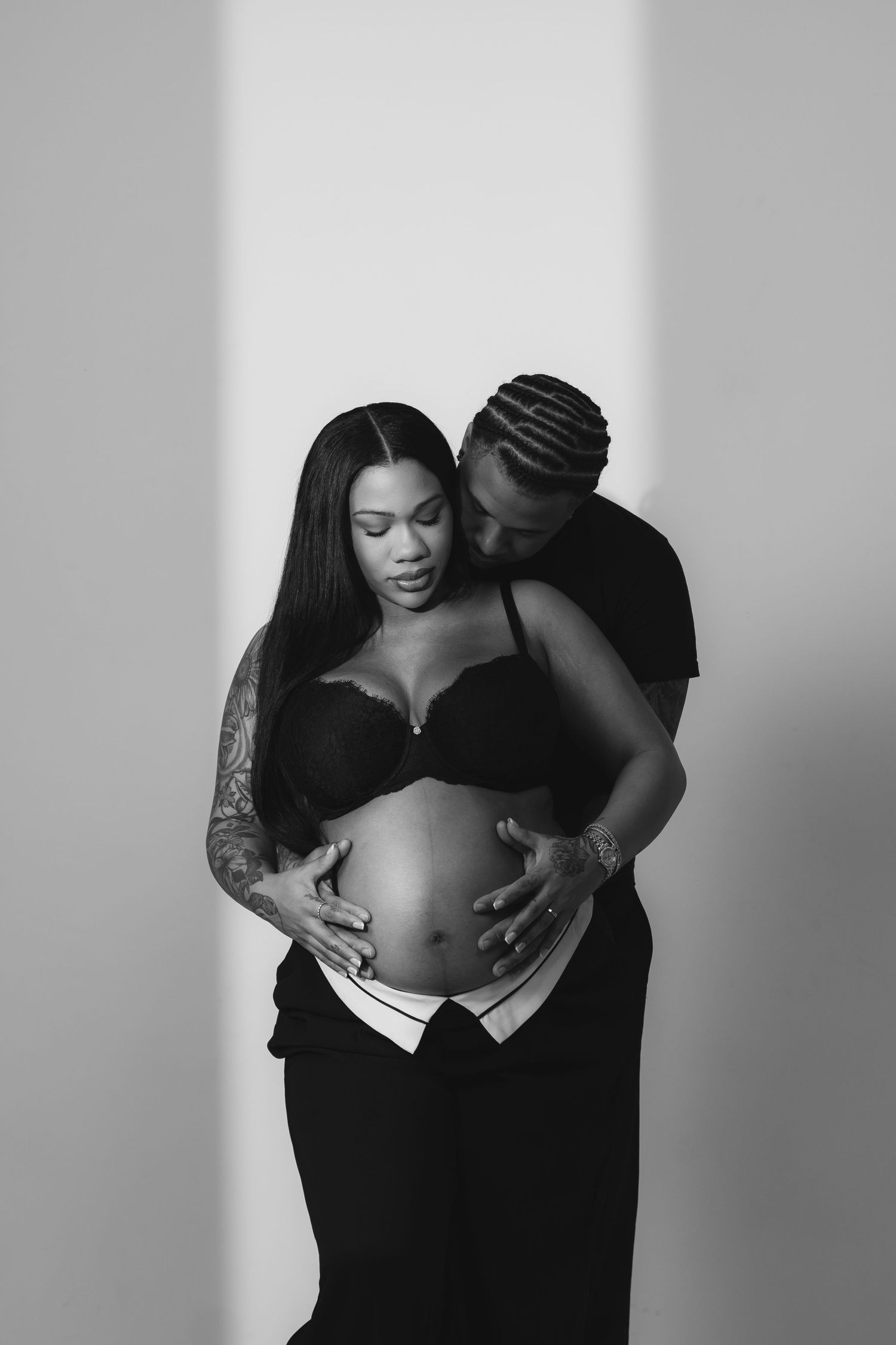 Black and white maternity photoshoot showing tender moments between a couple.