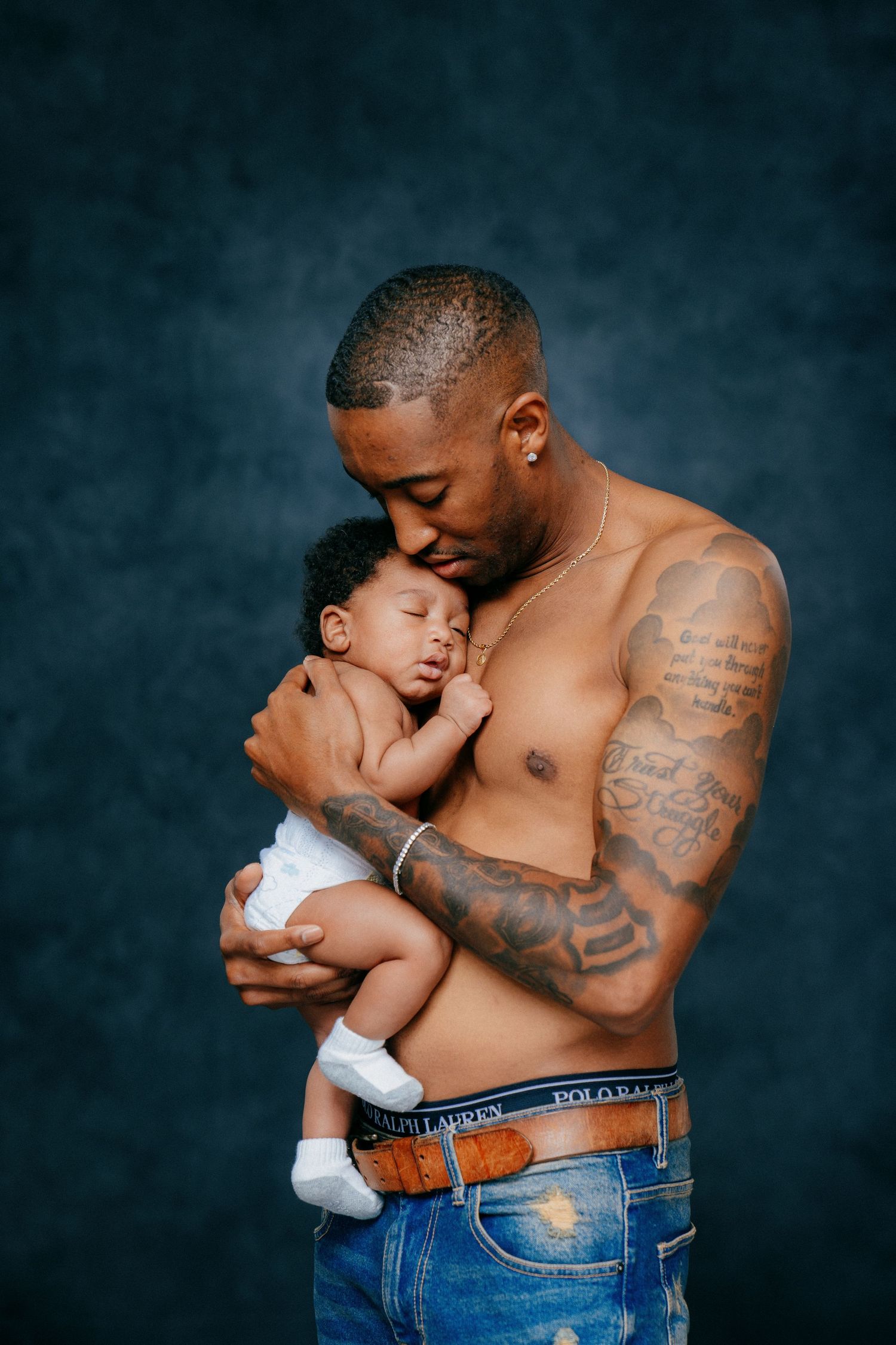 Intimate father and baby portrait series showing tender moments against dark backdrop.