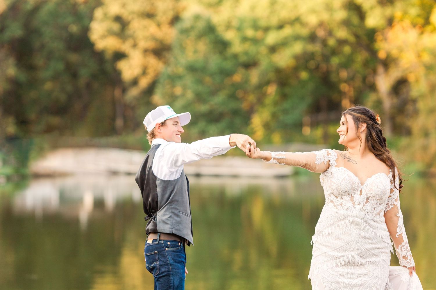 A couple holds hands and stands by a lake during their wedding photo shoot.