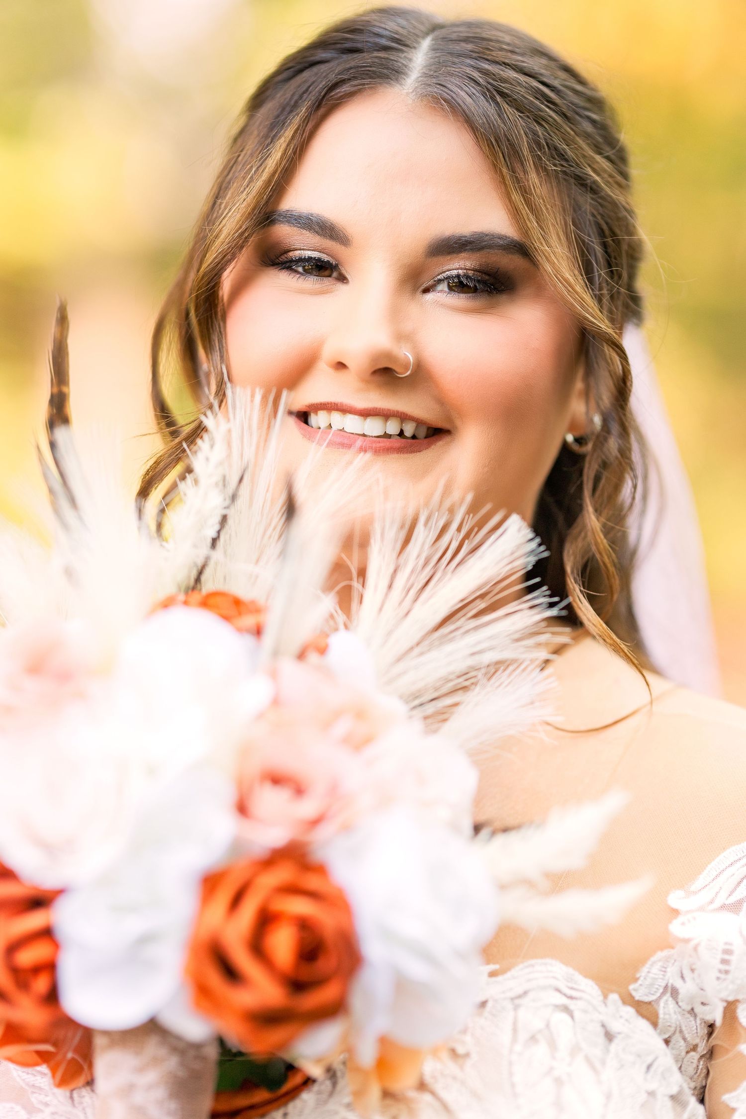 Bridal portrait showing elegant makeup and peach rose bouquet against autumn background.