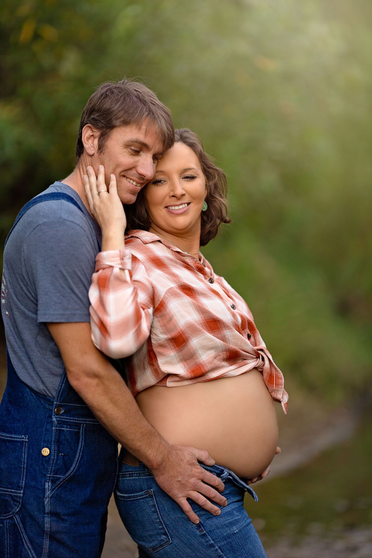 A joyful maternity portrait featuring a couple laughing together in nature.